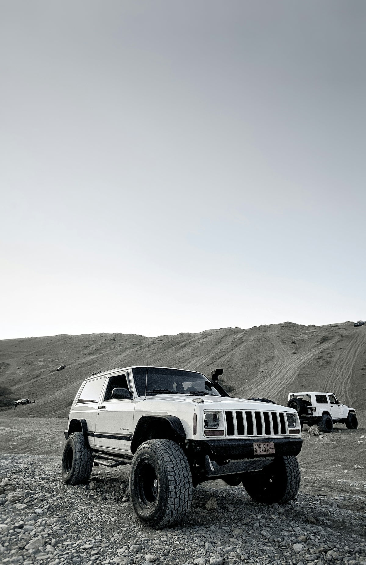 white jeep wrangler on gray sand during daytime