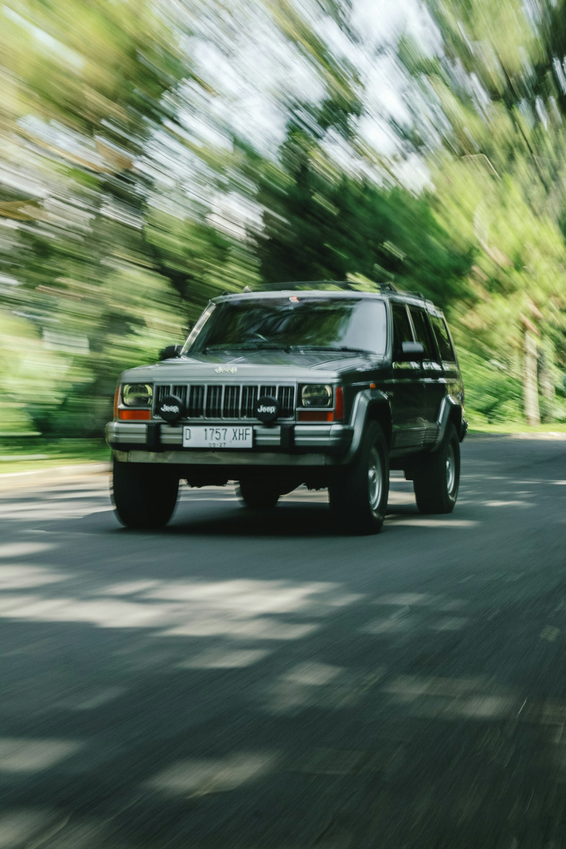 a black jeep driving down a street next to a forest