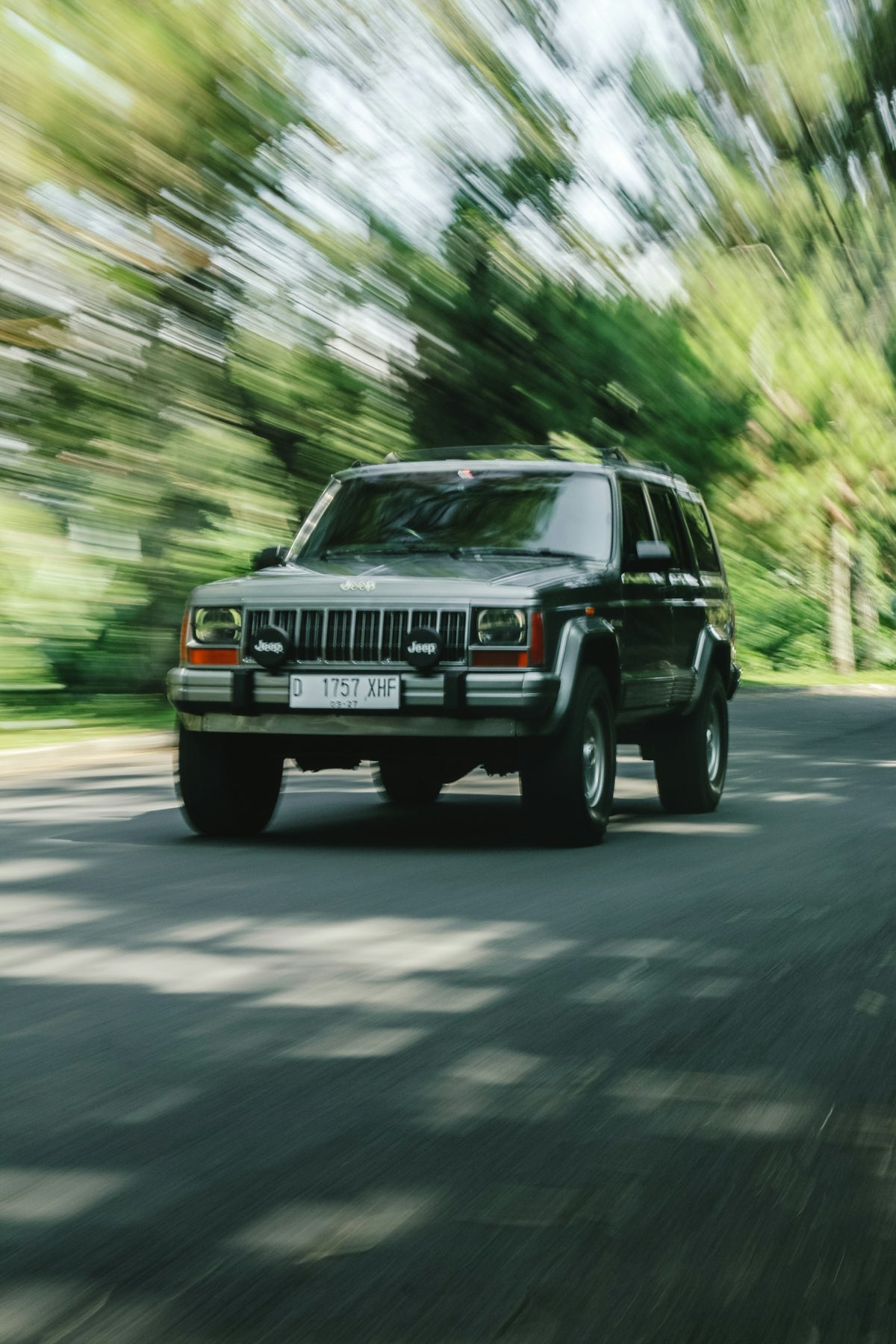 a black jeep driving down a street next to a forest