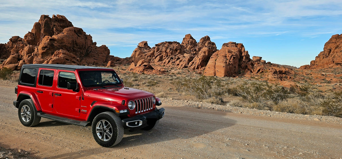 a red jeep driving down a dirt road