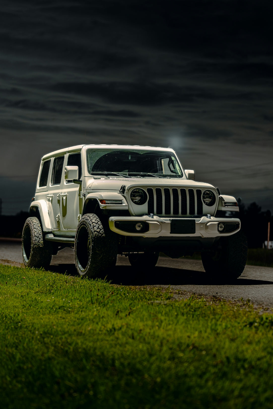 a white jeep driving down a road at night