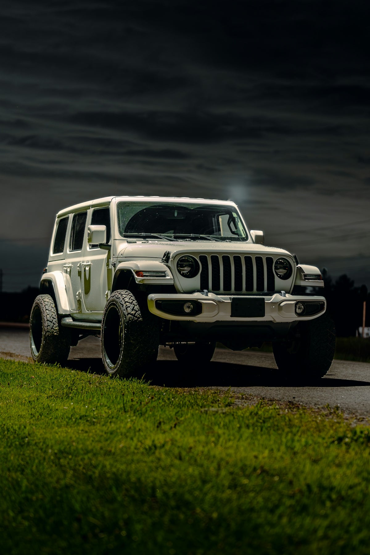 a white jeep driving down a road at night