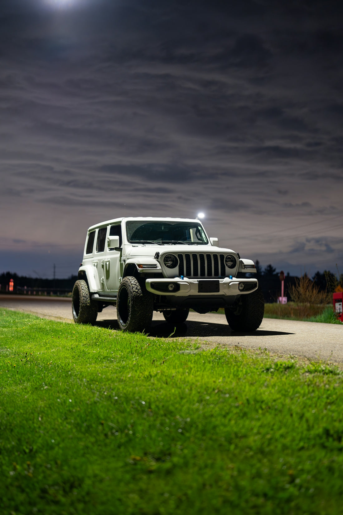a white jeep driving down a road at night