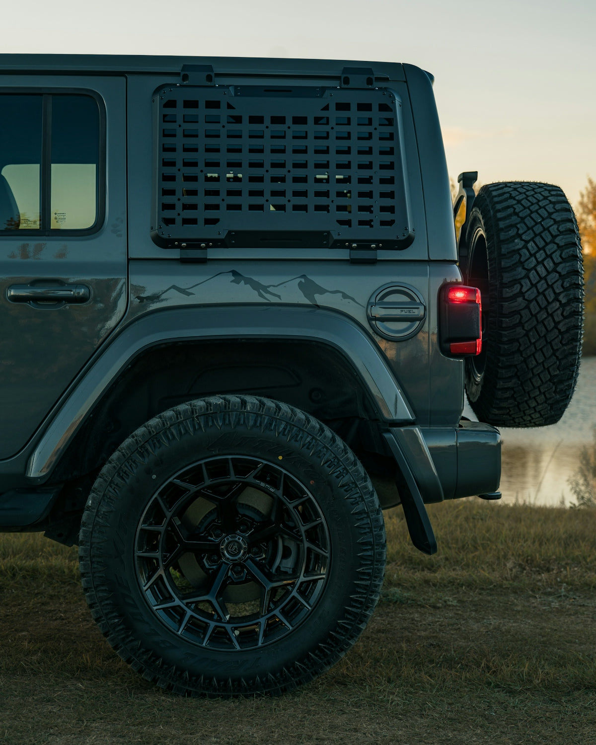 Gray jeep wrangler with spare tire and custom wheels