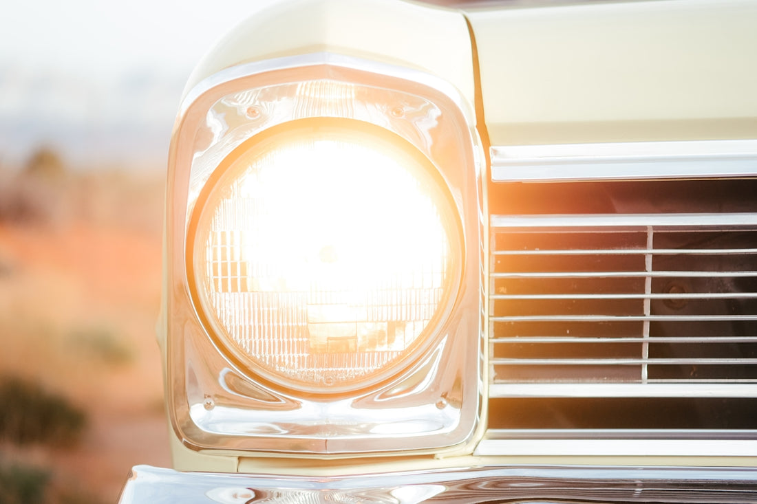 Close-up of a vintage car headlight illuminated at sunset