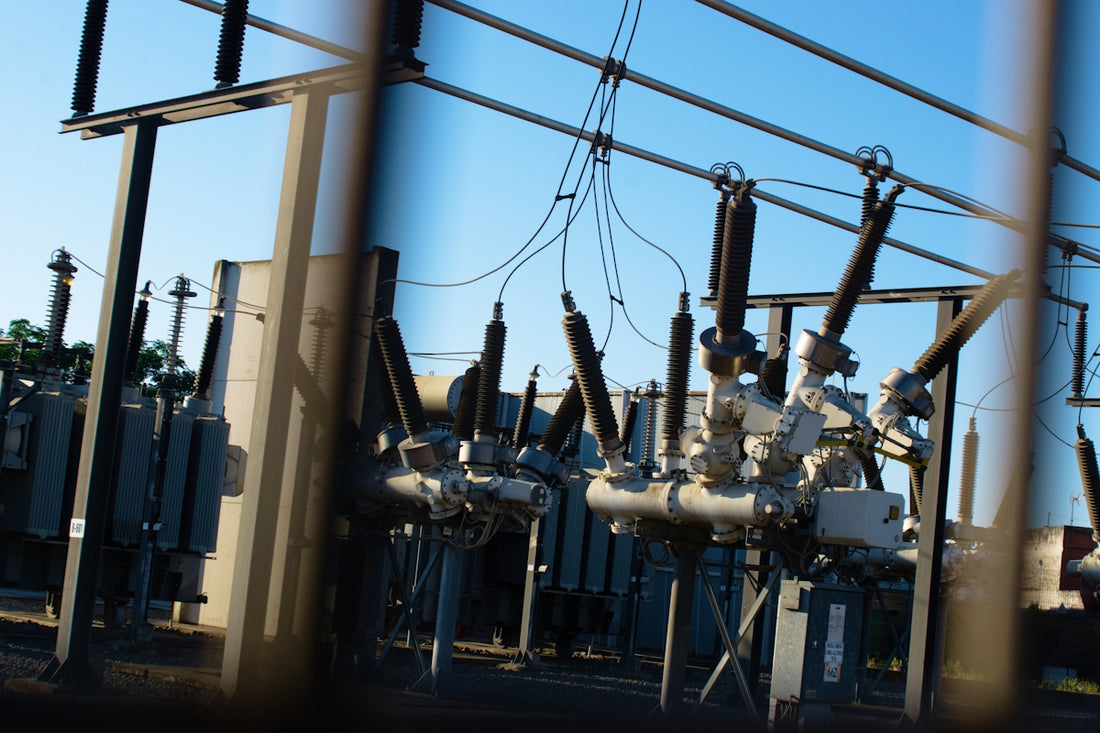 Electrical substation with transformers and power lines against blue sky.