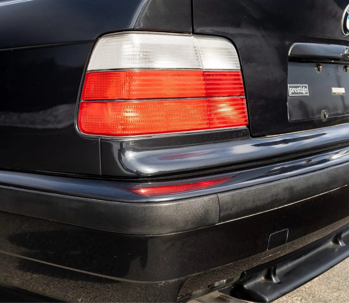 Euro style red/clear tail light installed on a black BMW E36 sedan