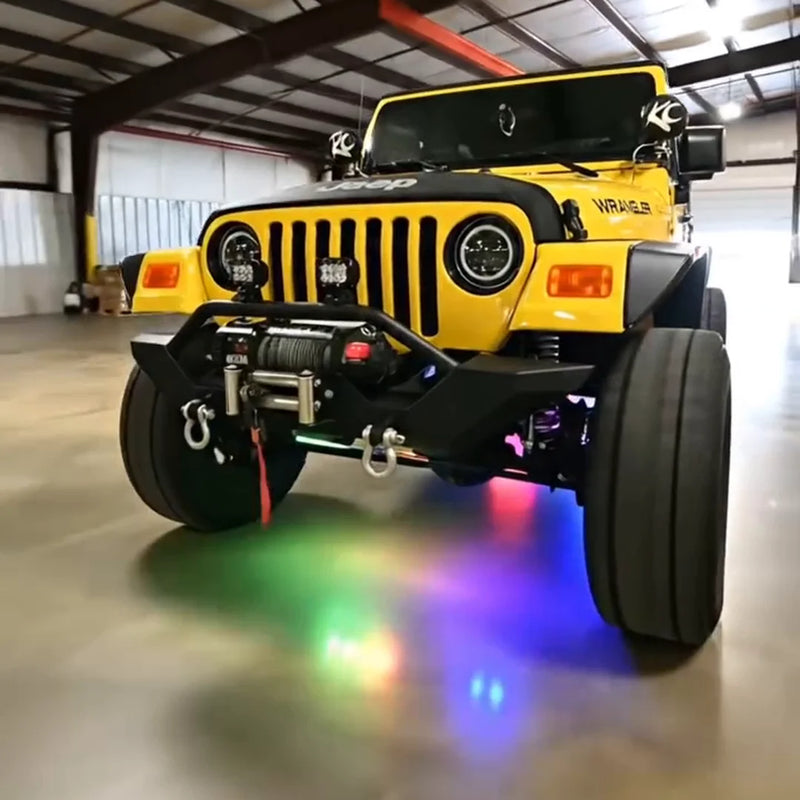 Yellow Jeep Wrangler with winch bumper and multicolor RGB rock lights glowing under it in a shop