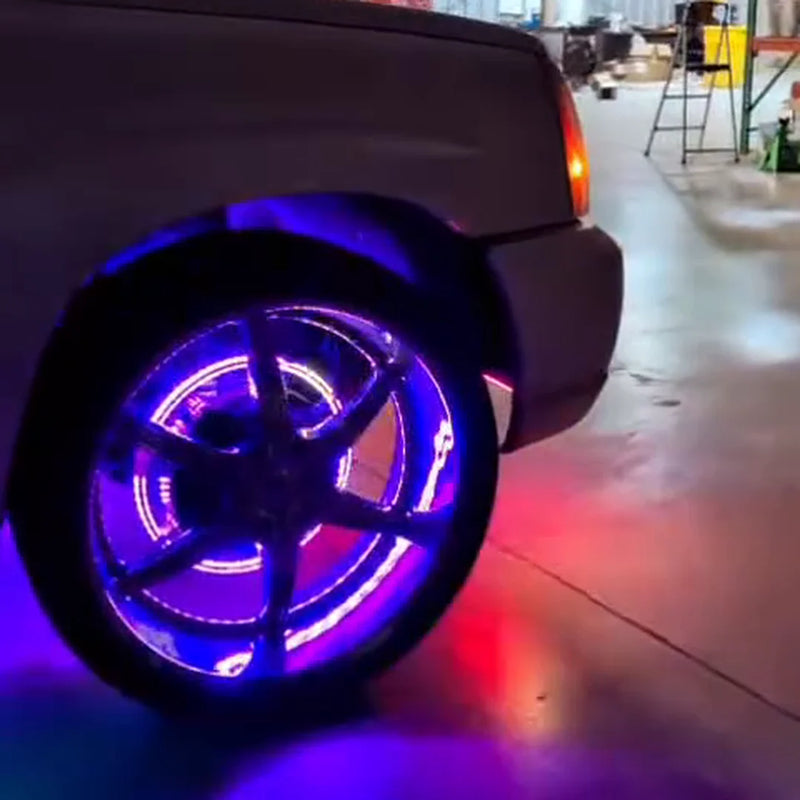 Rear wheel of a silver Cadillac Escalade lit by purple LED wheel ring lights